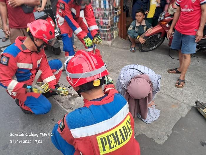 Waduh! Warga Kena Nyangkut di Sela Drainase saat Asyik Jalan di Jaktim, Damkar Turun Tangan