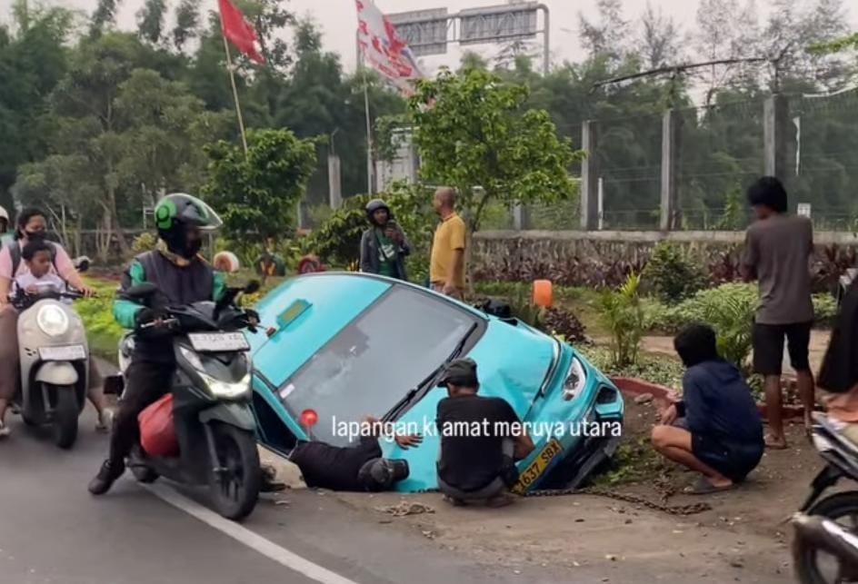 Taksi Listrik Tabrak Penjual Nasgor hingga Terperosok di Parit Jakbar